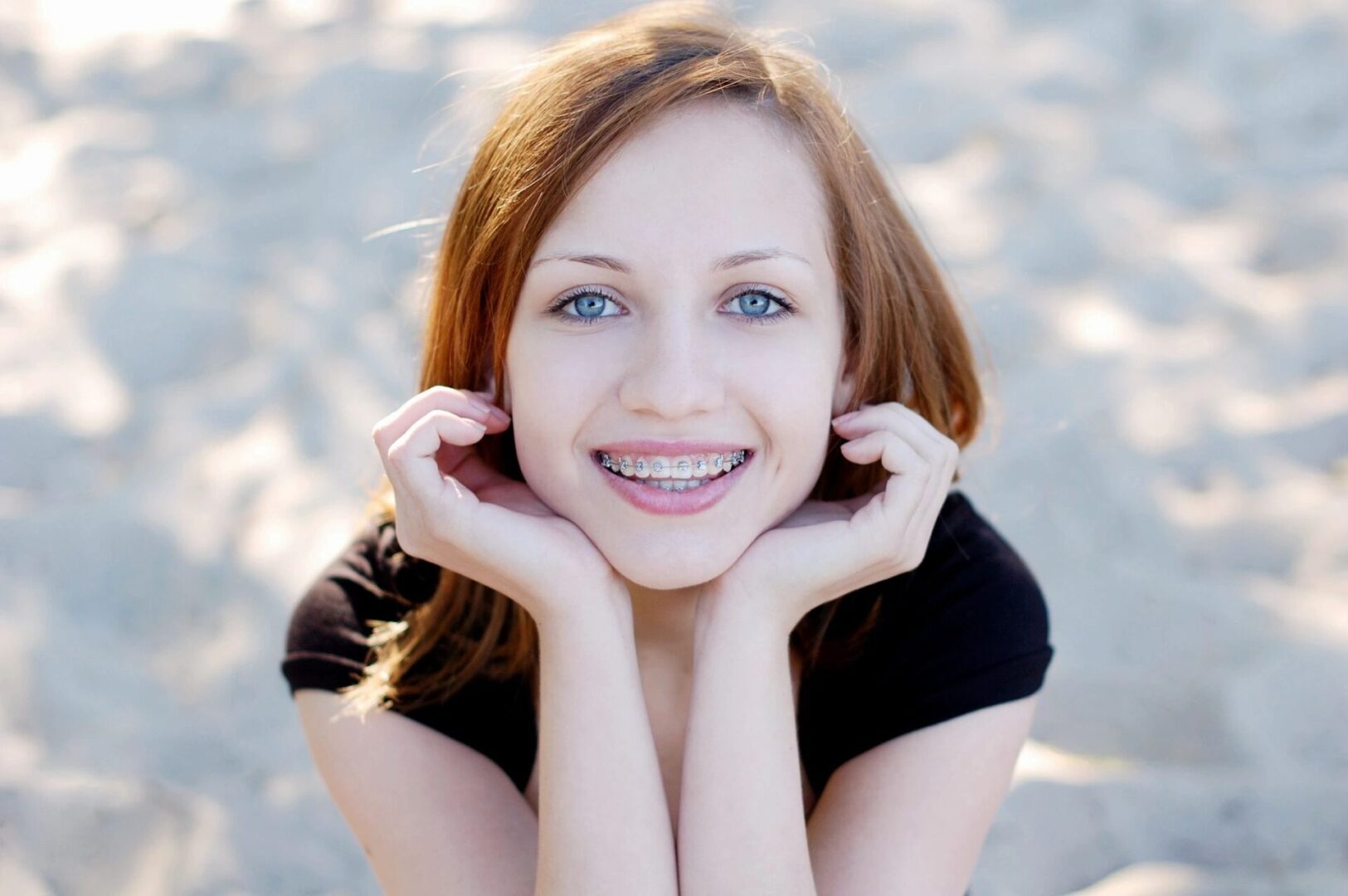 A woman with red hair and blue eyes smiling.