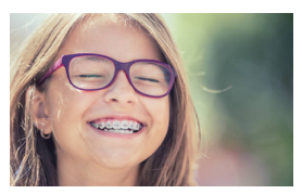 A girl with braces smiles for the camera.