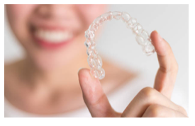 A woman holding an invisible aligner in her hand.