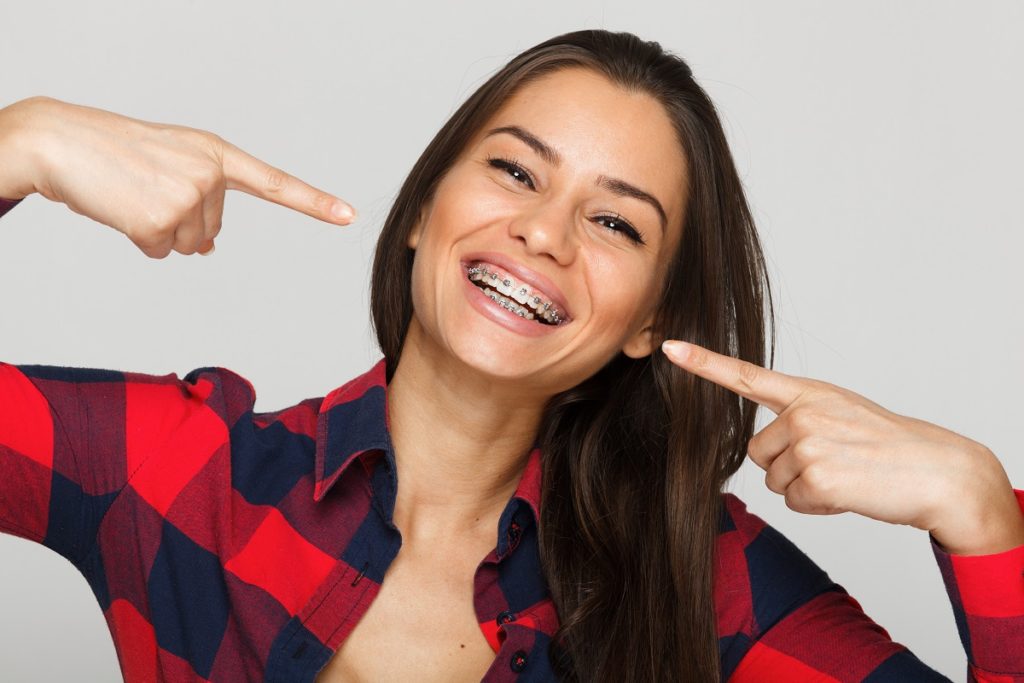 A woman with braces on her teeth pointing to the side.